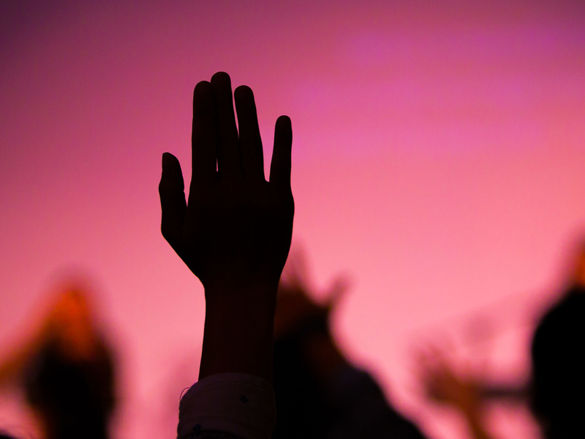 Silhouette of hands being raised up in a crowd
